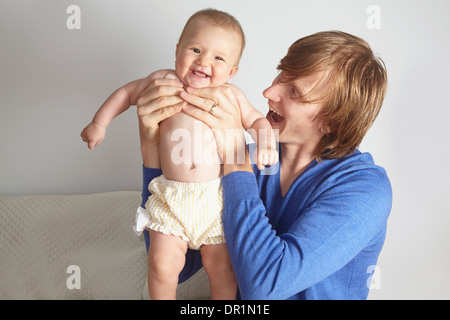 Father holding baby on bed Stock Photo