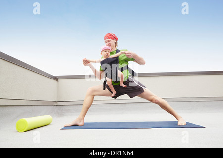 Father practicing yoga and holding baby Stock Photo