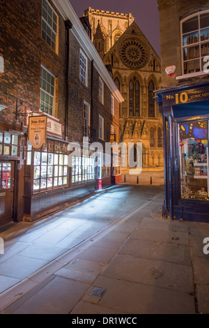 Evening view along Minster Gates to Minster's south entrance, a quaint, narrow lane lined with shops, some lit up - York North Yorkshire England, UK.r Stock Photo