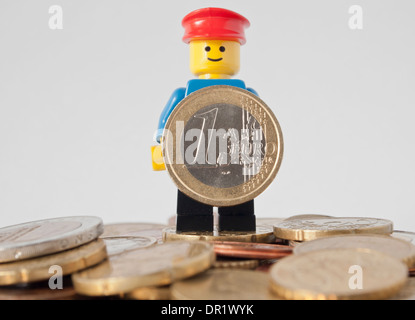 Smiling LEGO man holding up EURO coin Stock Photo