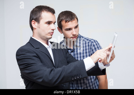 Two serious businessmen looking at digital tablet. Stock Photo