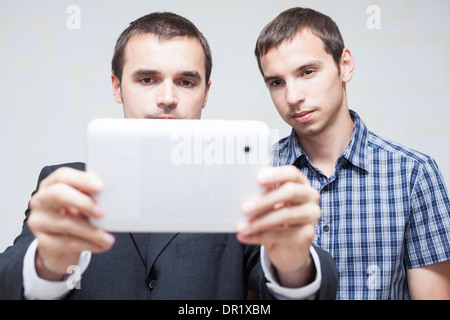 Two serious businessmen looking at digital tablet. Stock Photo