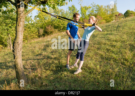 A woman uses suspension rings on a meadow Stock Photo