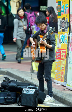 Young Chinese Street Performer Plays the Guitar in Mong Kok, Hong Kong. Stock Photo