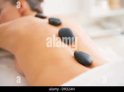 Closeup on young woman receiving hot stone massage. rear view Stock Photo