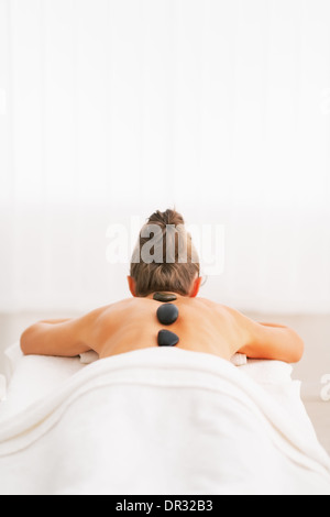 Young woman receiving hot stone massage. rear view Stock Photo