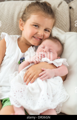 Baby girl wearing a dress in sisters arms Stock Photo
