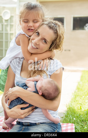 Mother and two daughters hugging outside Stock Photo