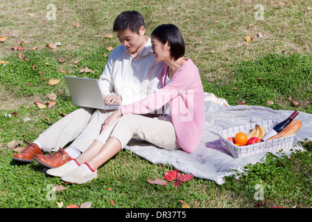 Mid adult couple using laptop in park Stock Photo