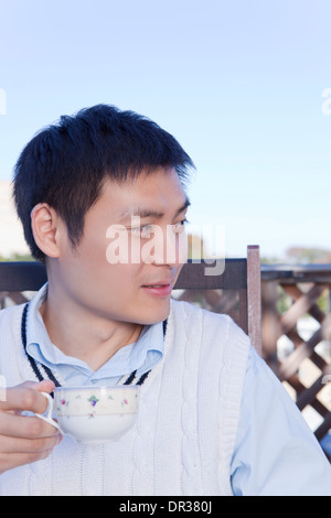 Mid adult man having tea on balcony Stock Photo