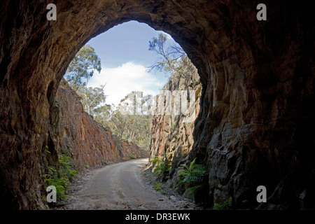 Narrow dirt road leading through arched stone entrance to disused railway tunnel at Newnes near Lithgow, NSW Australia Stock Photo