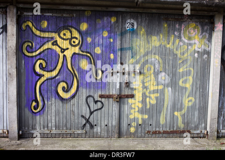 Octopus like yellow alien graffiti on an old garage wooden door in Warsaw, Poland. Stock Photo