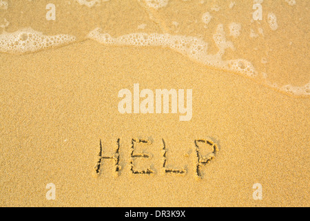 Help, written in sand on beach texture - soft wave of the sea. Stock Photo