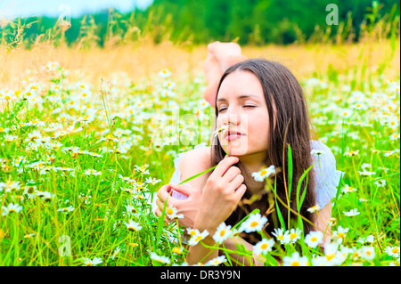 woman lying in a field and smelling a daisy Stock Photo