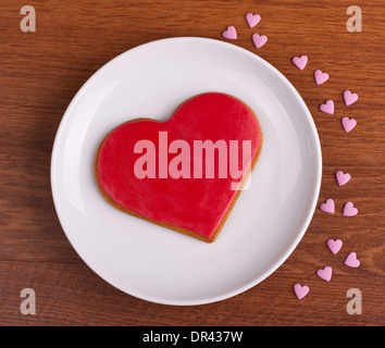 Heart shaped gingerbread cookie on white plate shot from above Stock Photo