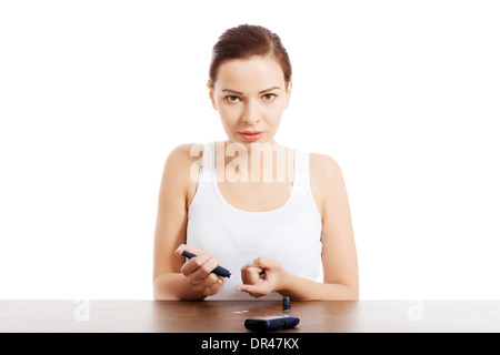 Young beautiful woman doing sugar level test. Over white background. Stock Photo