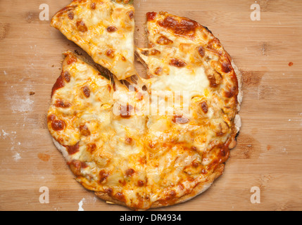 Whole cheese pizza with first slice being taken Stock Photo