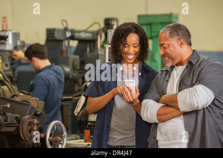 Workers using cell phone in warehouse Stock Photo