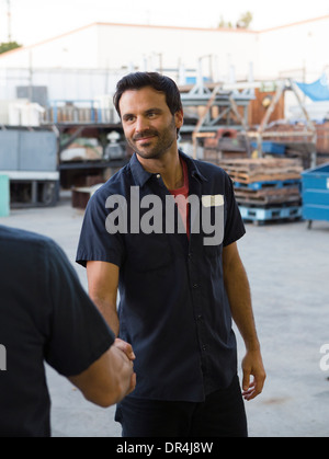 Workers shaking hands in warehouse Stock Photo