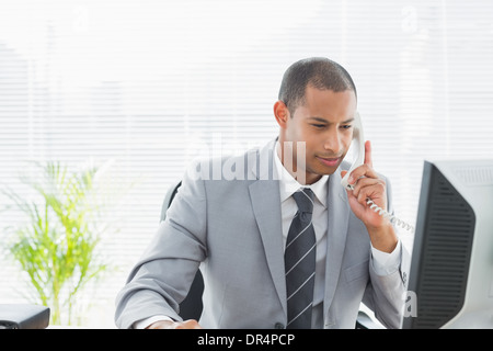 Businessman using computer and phone at office Stock Photo