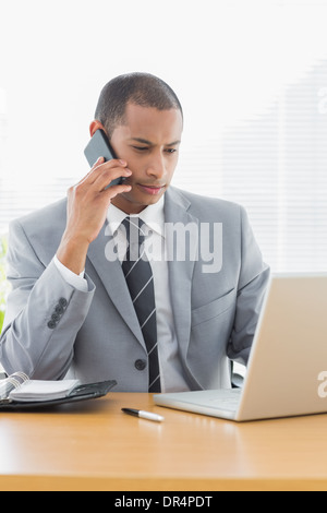 Businessman using laptop and cellphone at office Stock Photo