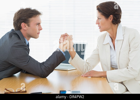Serious business couple arm wrestling at office desk Stock Photo