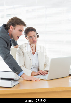 Business couple using laptop at office desk Stock Photo