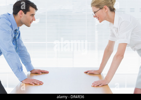 Smiling business couple looking at each other with palms at desk Stock Photo