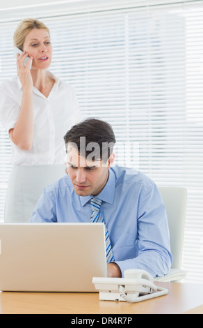 Businesswoman and man using cellphone and laptop at office Stock Photo