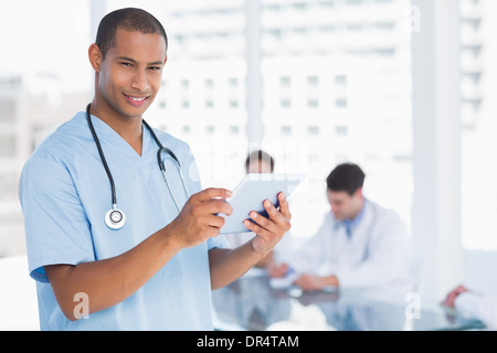 Murgeon using digital tablet with group around table in hospital Stock Photo