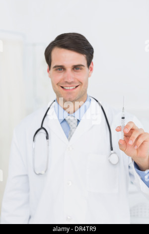 Young handsome man holding syringe smiling happy and positive, thumb up ...