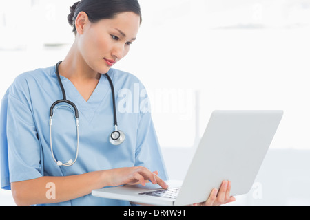 Concentrated surgeon using a laptop in hospital Stock Photo