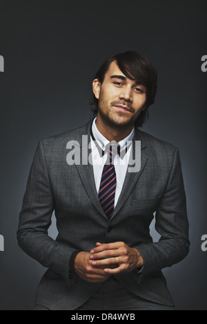 Portrait of good looking young man wearing business suit posing against black background. Confident young businessman. Stock Photo