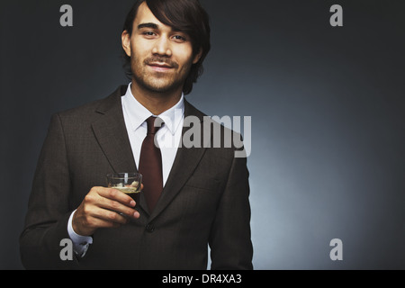 Image of charming young businessman holding black coffee. Male model in suit holding cup of coffee against black background Stock Photo
