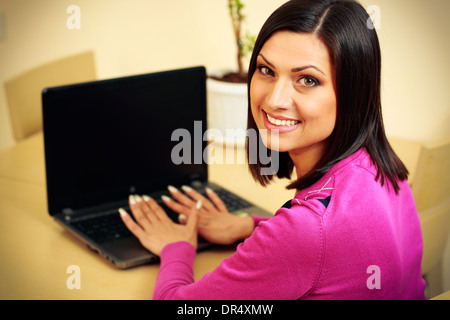 Middle-aged smiling woman using laptop and looking on the camera Stock Photo