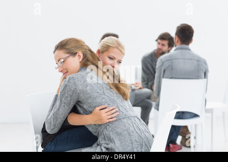 Group therapy session with therapist and client hugging Stock Photo