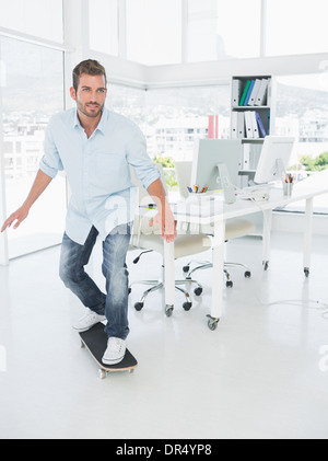 Happy young man skateboarding in office Stock Photo