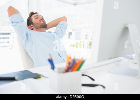 Casual man resting with hands behind head in office Stock Photo
