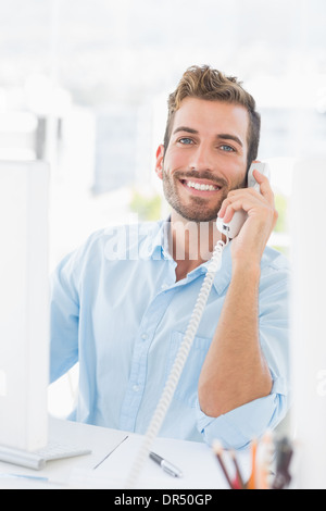 Smiling young man using phone and computer Stock Photo