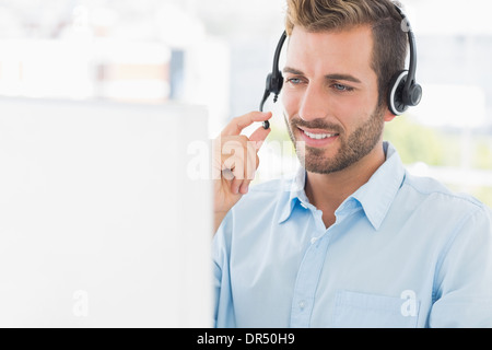 Close-up of a casual young man with headset using computer Stock Photo
