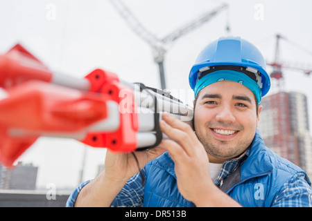 Mixed race worker carrying metal on construction site Stock Photo
