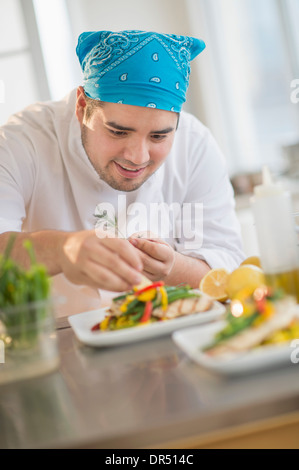 Mixed race chef plating food in restaurant Stock Photo