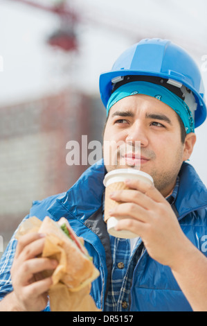 Mixed race worker eating lunch on construction site Stock Photo