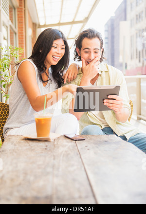 Couple using digital tablet at sidewalk cafe Stock Photo