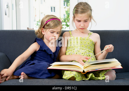 Children Looking At Photo Album In Living Room Stock Photo