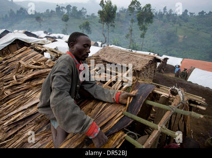 Dec 19, 2008 - Masisi, Democratic Republic of Congo - Habiraimana Gakuru repairs the roof on his family's hut in the Lushubere camp, 10 km (6 miles) east of Masisi, on Friday, December 19, 2008. 'I suffer here because I miss the food we had in Karongi,' said Gakuru, who left his fields behind when he fled with his wife and six children after fighting broke out near his home. (Credi Stock Photo