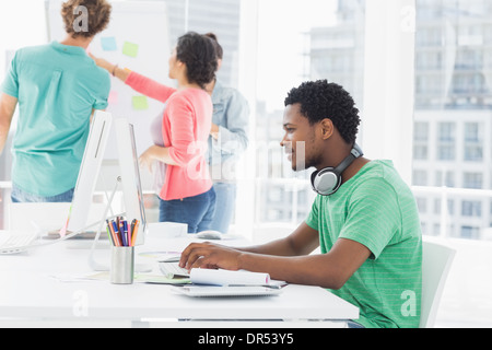 Casual man using computer with group of colleagues behind in office Stock Photo