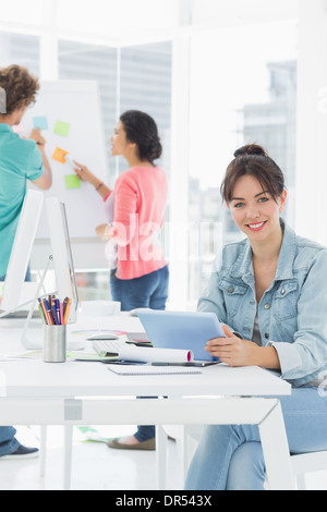 Casual woman using digital tablet with colleagues behind in office Stock Photo