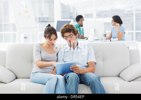Couple using digital tablet with colleagues at creative office Stock Photo