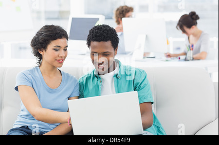 Couple using laptop with colleagues at creative office Stock Photo